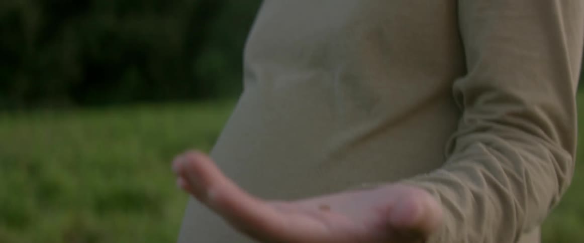 A woman is looking down at a bug in her hand