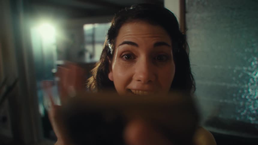A young woman picking up a video call on her smartphone and waving hello