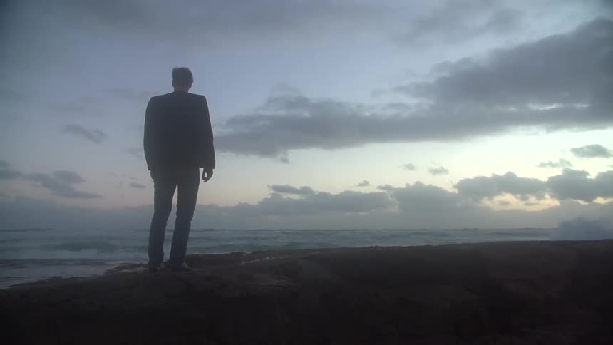 Man stands on the rocks by the shore