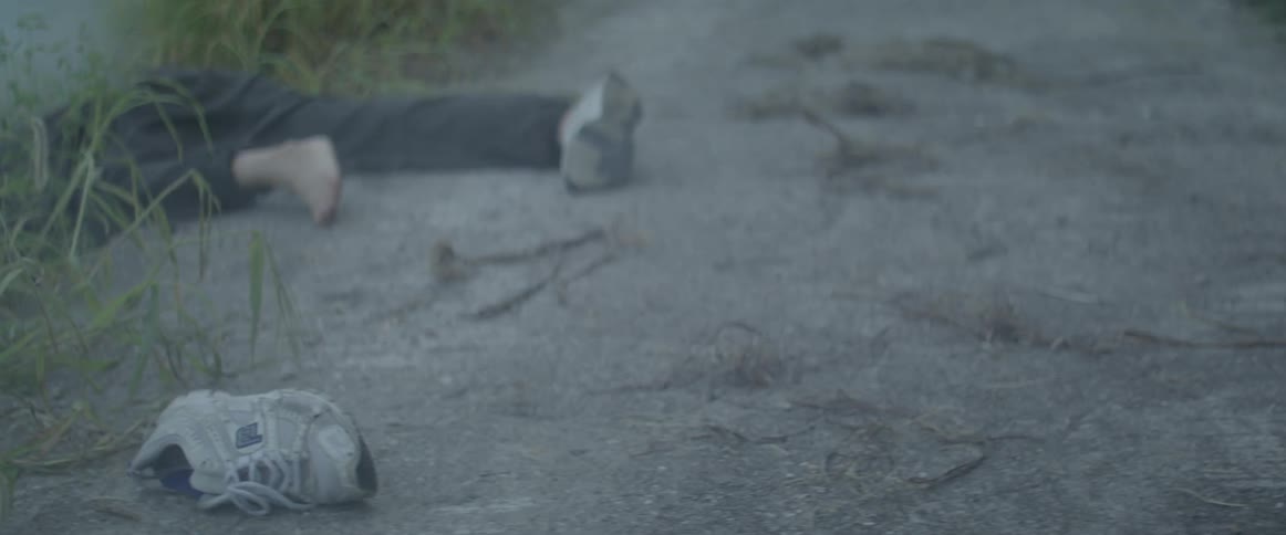A person laying in the road with one shoe off and he isn't moving
