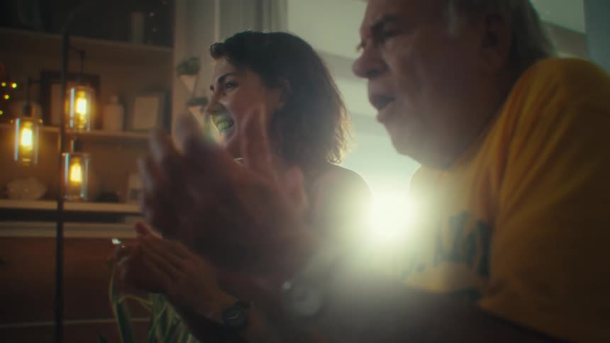 A man and woman clap and have fun watching something