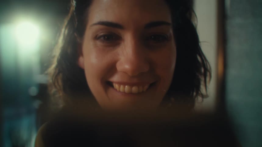 Smiling woman talking in front of a smartphone