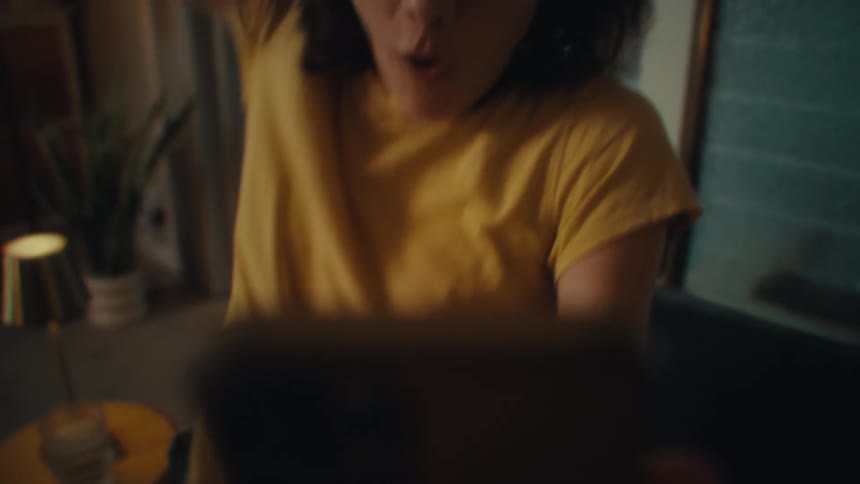 The woman gets very excited and jumps up while using her phone