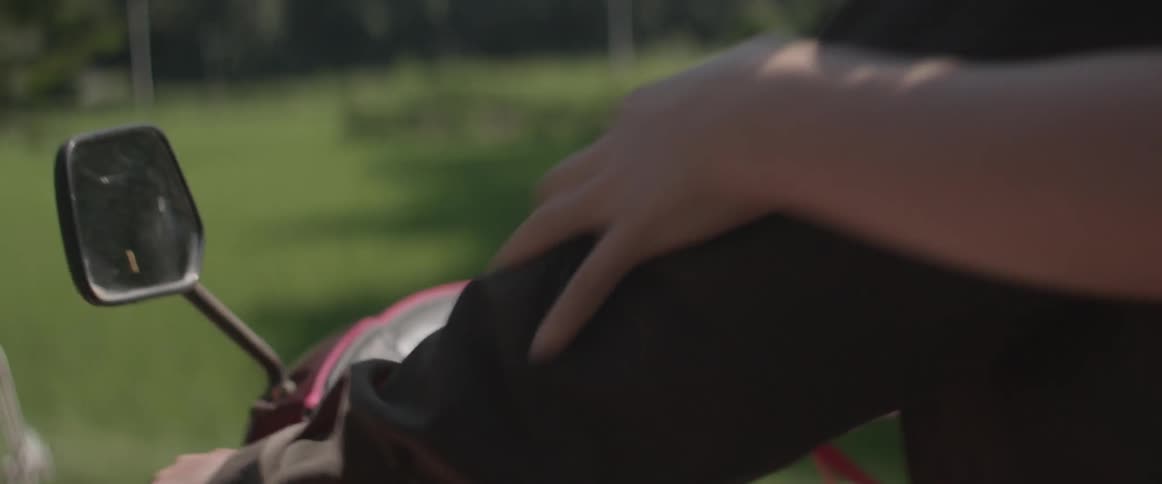 A woman holds onto a man as they ride on a motorcycle