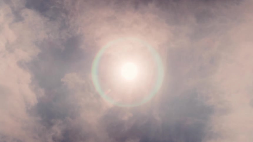 The sun shines brightly through wispy clouds creating a halo effect in the sky