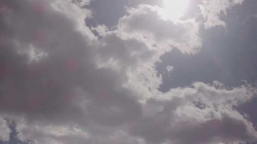 Bright sun shining between light clouds in the sky