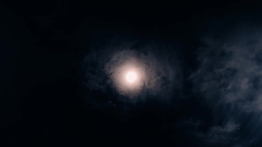 The video shows a bright light source in the middle of a dark background with a subtle lens flare effect the light is slightly diffused by a ring of glowing mist around it