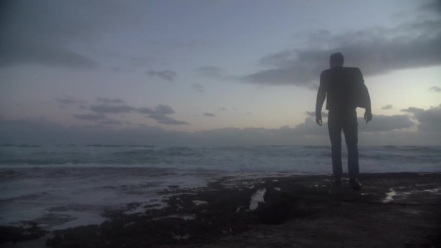 Man walks on rocks by the shore