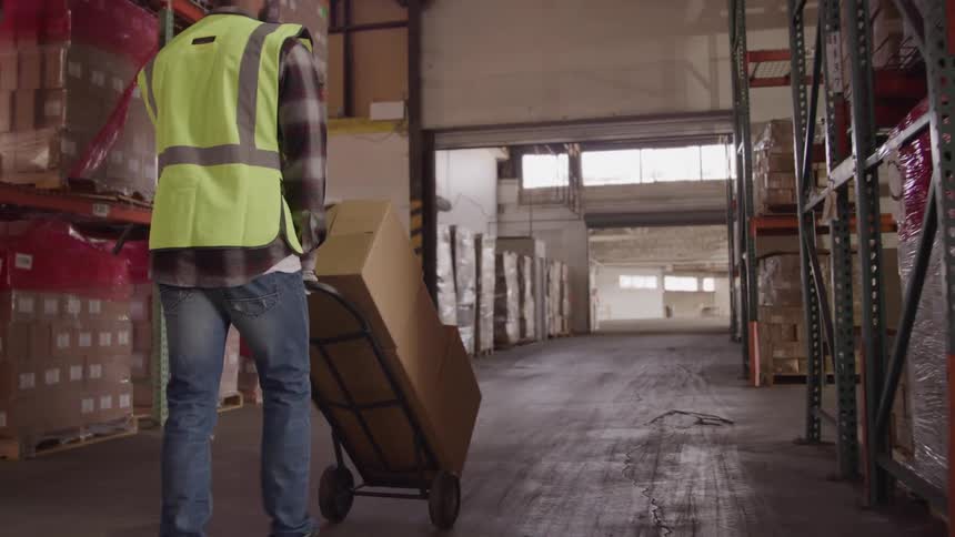 Man and a warehouse carrying a cart with boxes