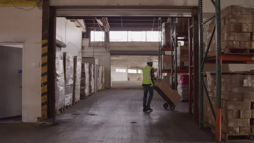 Worker moving a box with a dolly in a warehouse