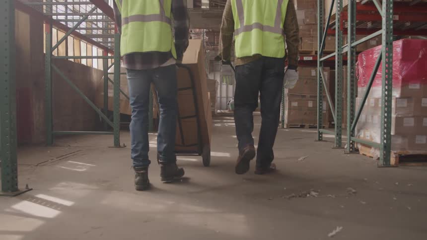 Two people walking in a warehouse with a distribution center and boxes