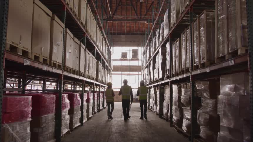 Three workers are talking in the storage facility