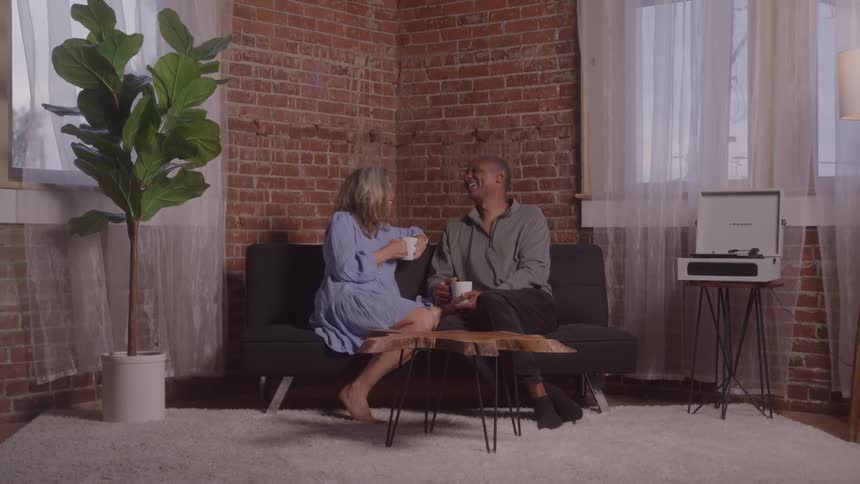 Two people chatting on a couch over a cup of coffee