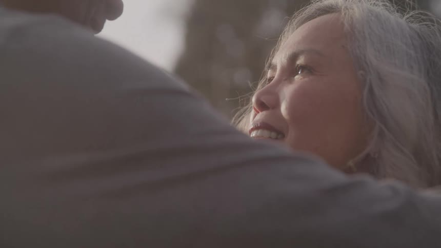 Closeup of a black man happily hugging his female partner while standing outdoors during daytime