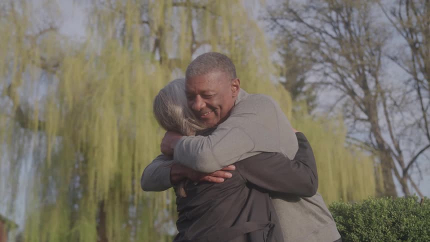 Two people hugging outdoors on a sunny day