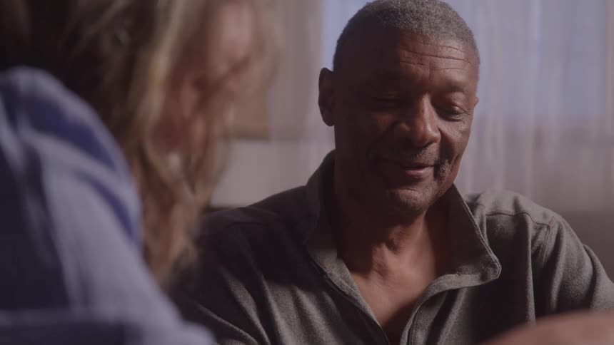 Man smiling while talking to a woman blurred in the foreground