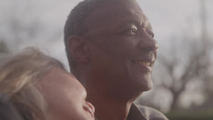 Man smiling while looking at the horizon with a child in his arms