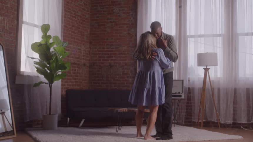 A man and woman are dancing in the living room