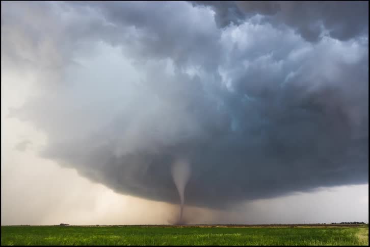 Tornado forms beneath dark clouds over an open plain