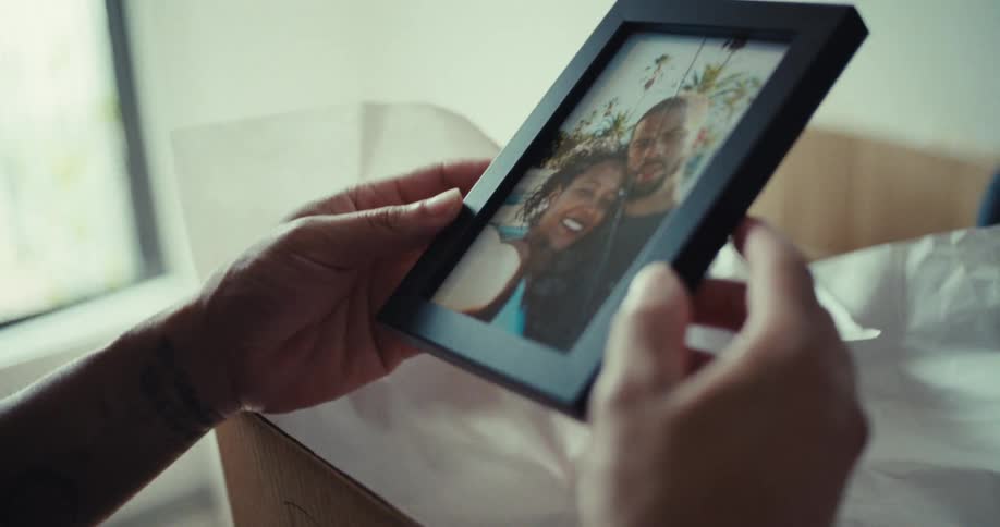 A person holds a framed photo of a smiling couple