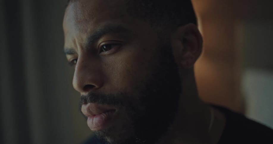 The face of a bearded man staring straight ahead and blinking his eyes