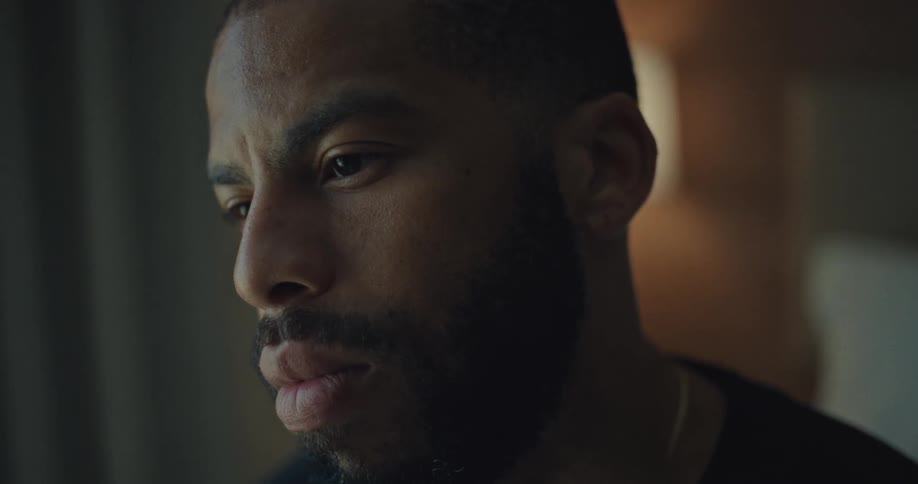 The video shows a closeup of a mans face with a focused and serious expression the lighting is soft creating a slightly dramatic and contemplative mood