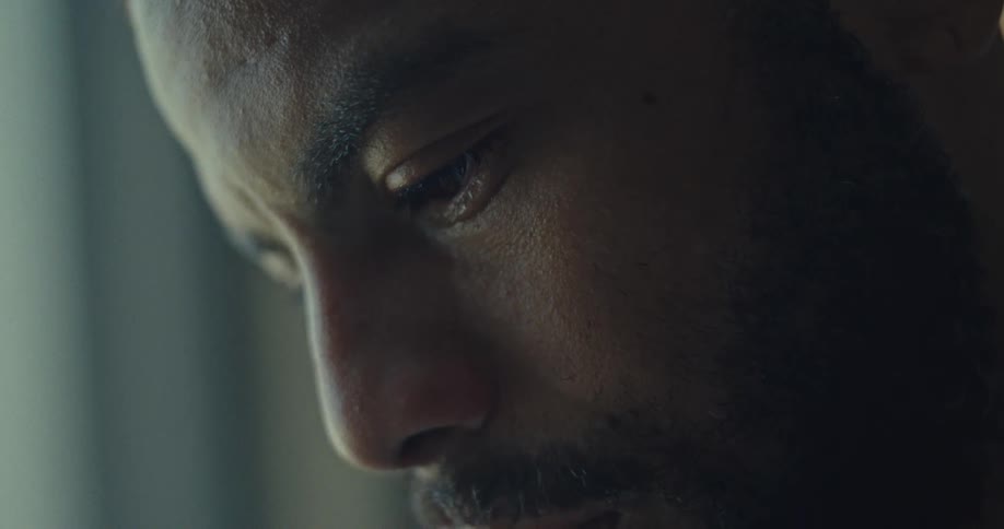 Close up of a young black man crying in a room during daytime