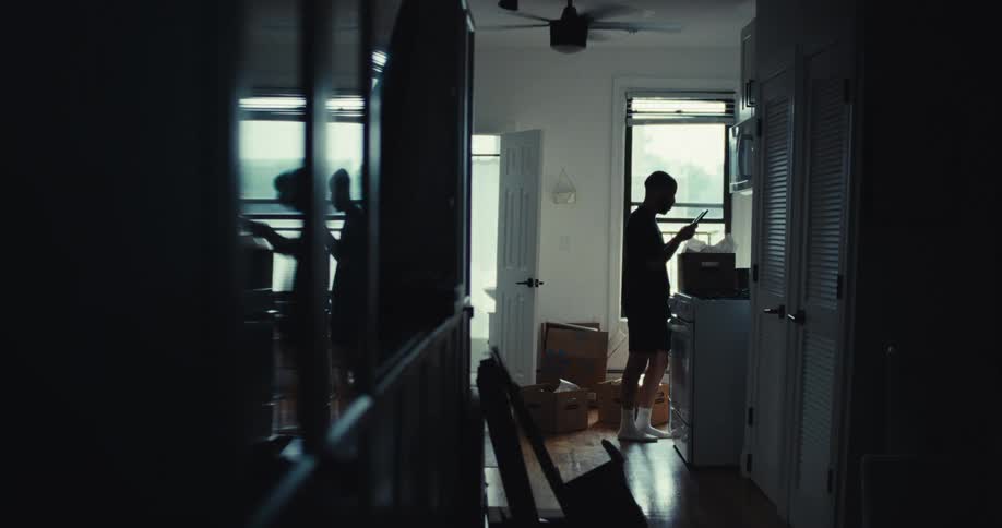 Man standing in his kitchen pulls an item from a box and looks over it