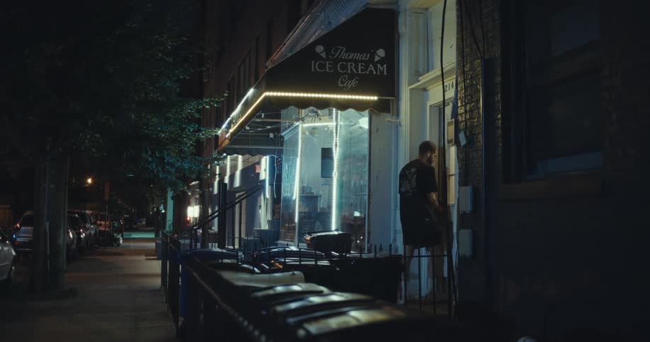 Man entering a door next to an ice cream shop at night