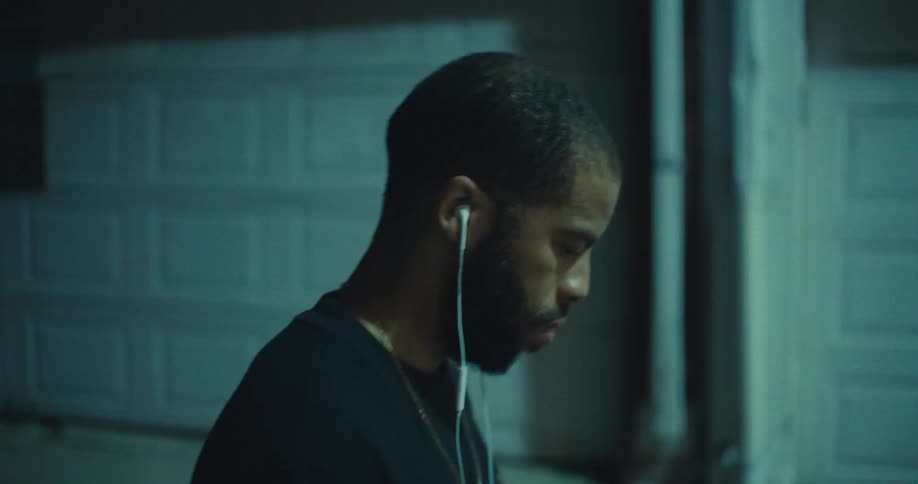 Man with wired headphones walking on the street at night