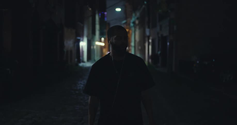 Man walks through a narrow dark street at night
