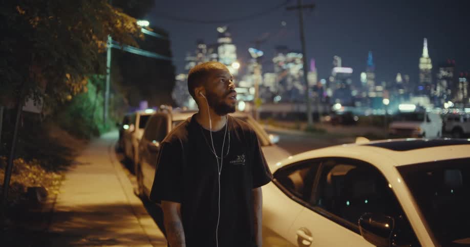 Man with headphones walking on city sidewalk at night