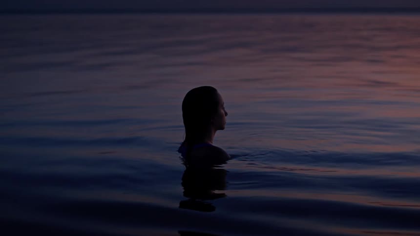 Person swimming in the sea at sunset