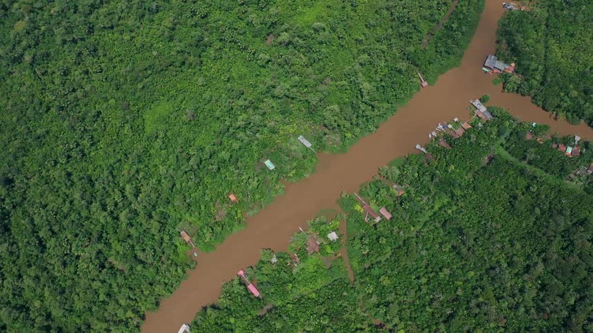 Muddy river winds through forest and houses