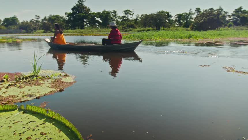 View from a boat on a lilycovered waterway with another boat and two people in the distance