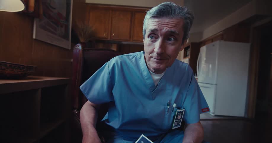 A man in scrubs shows a patient a pamphlet in his living room