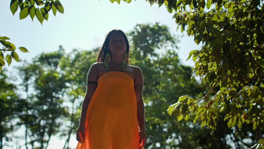 Woman in orange dress among vegetation viewed from below