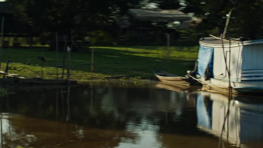 A boat is docked by a lake in a rural area at midday