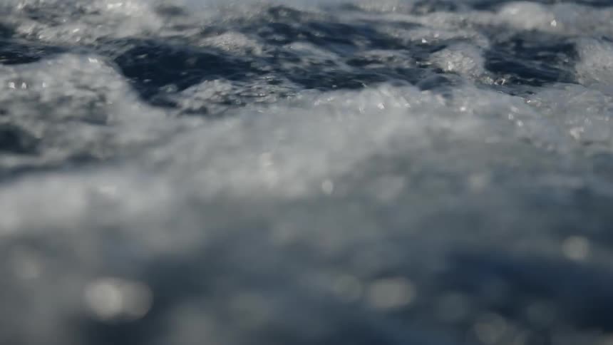 Closeup view of foamy ocean water moving across the surface