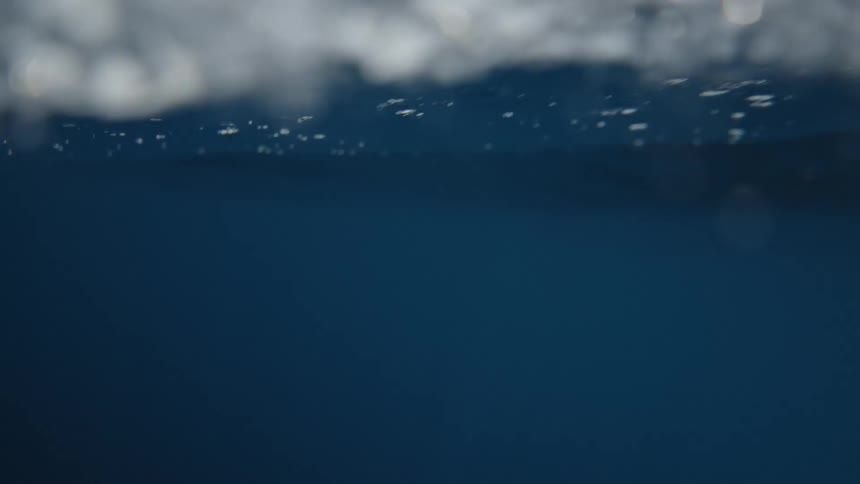 Ocean waves roll and crash across the water under a clear sky