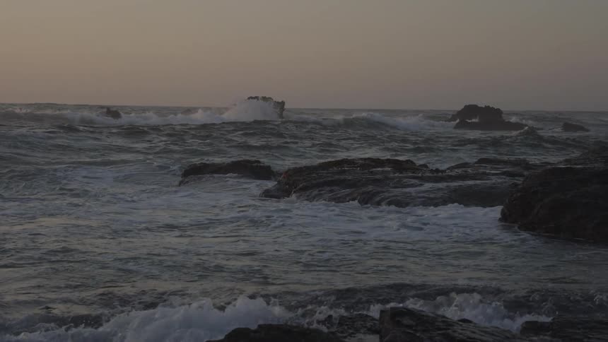 A beach with many rocks and rough seas