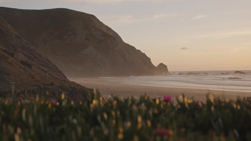 A quiet beach backed by steep coastal cliffs at sunset