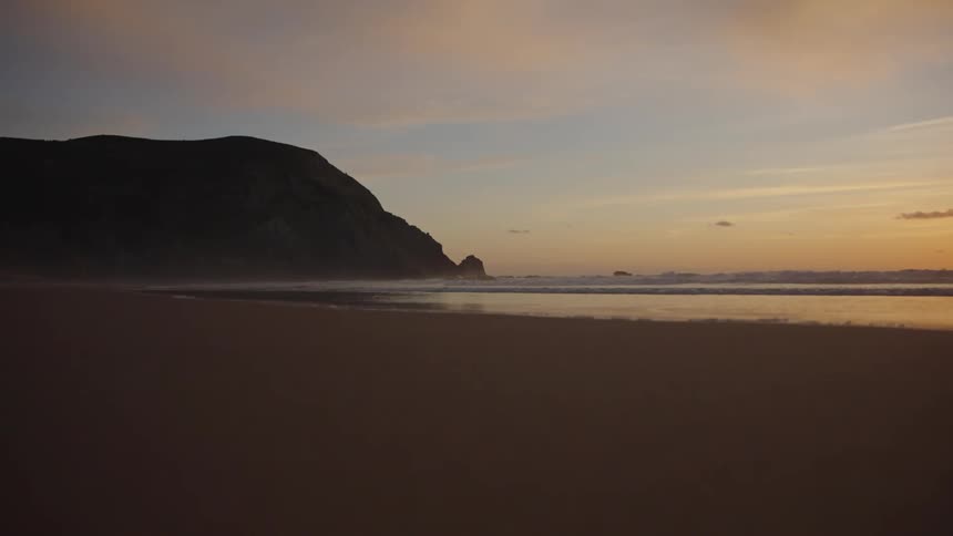 A beach in the late afternoon with calm waves in the sea