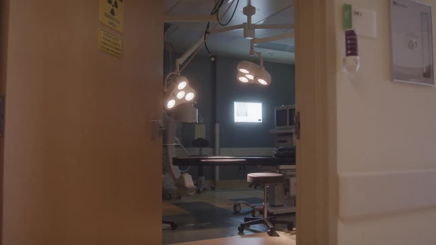 Empty operating room with surgical lights on seen through an open door