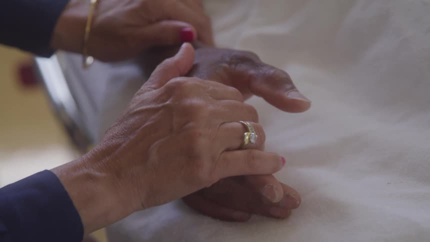 A visitor holds hands with a hospital patient