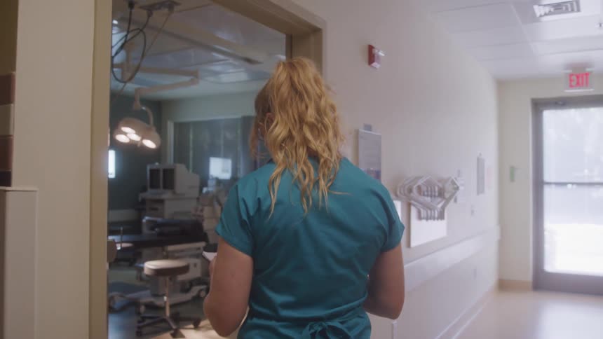 Healthcare professional walks toward a procedure room with a radiation sign on the door