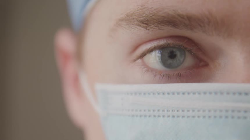 Blue eye of a person wearing a surgical mask