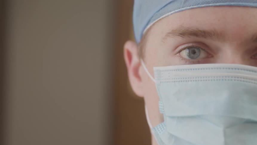 Closeup of a healthcare professional wearing a surgical mask and cap