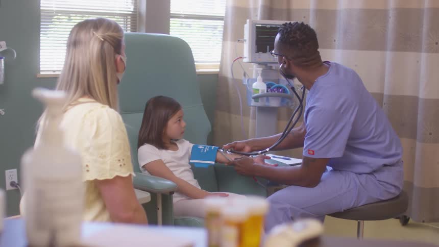 Little girl having a her blood pressure taken by a male nurse