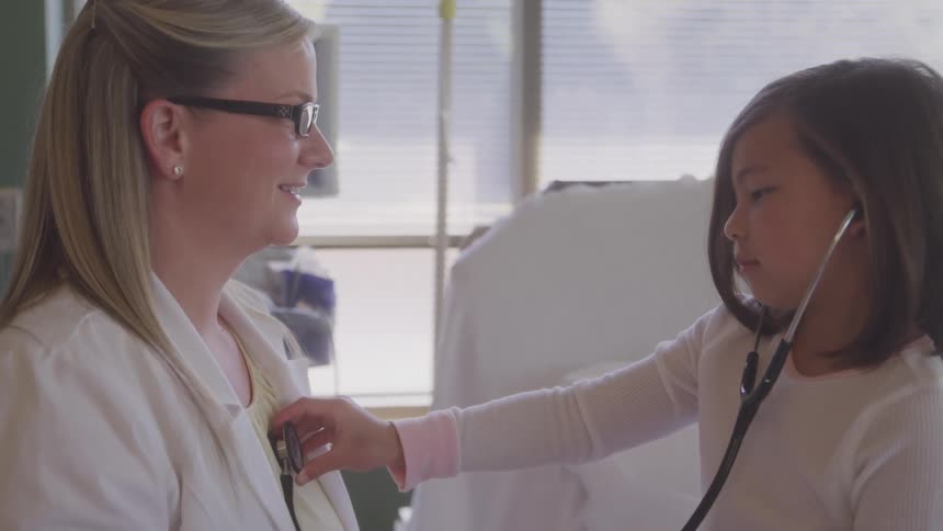 Girl using a stethoscope to listen to a healthcare professionals heartbeat